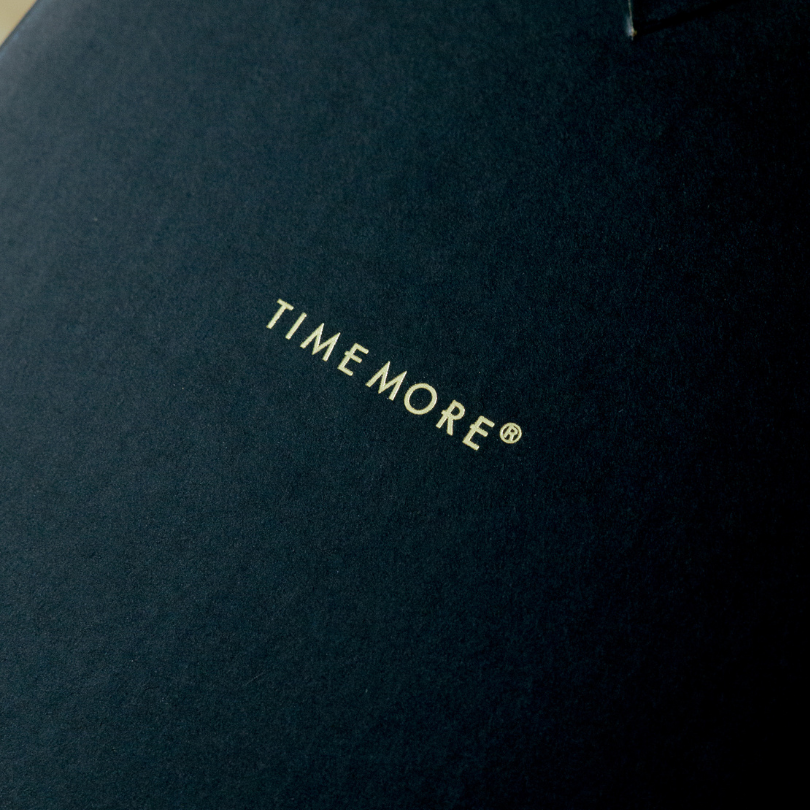 Close-up of a dark blue fabric with 'TIMEMORE' logo embroidered on it.