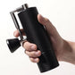 Hand holding a black pepper grinder on a white background