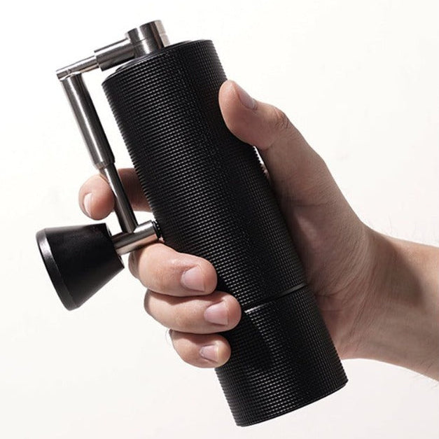 Hand holding a black pepper grinder on a white background