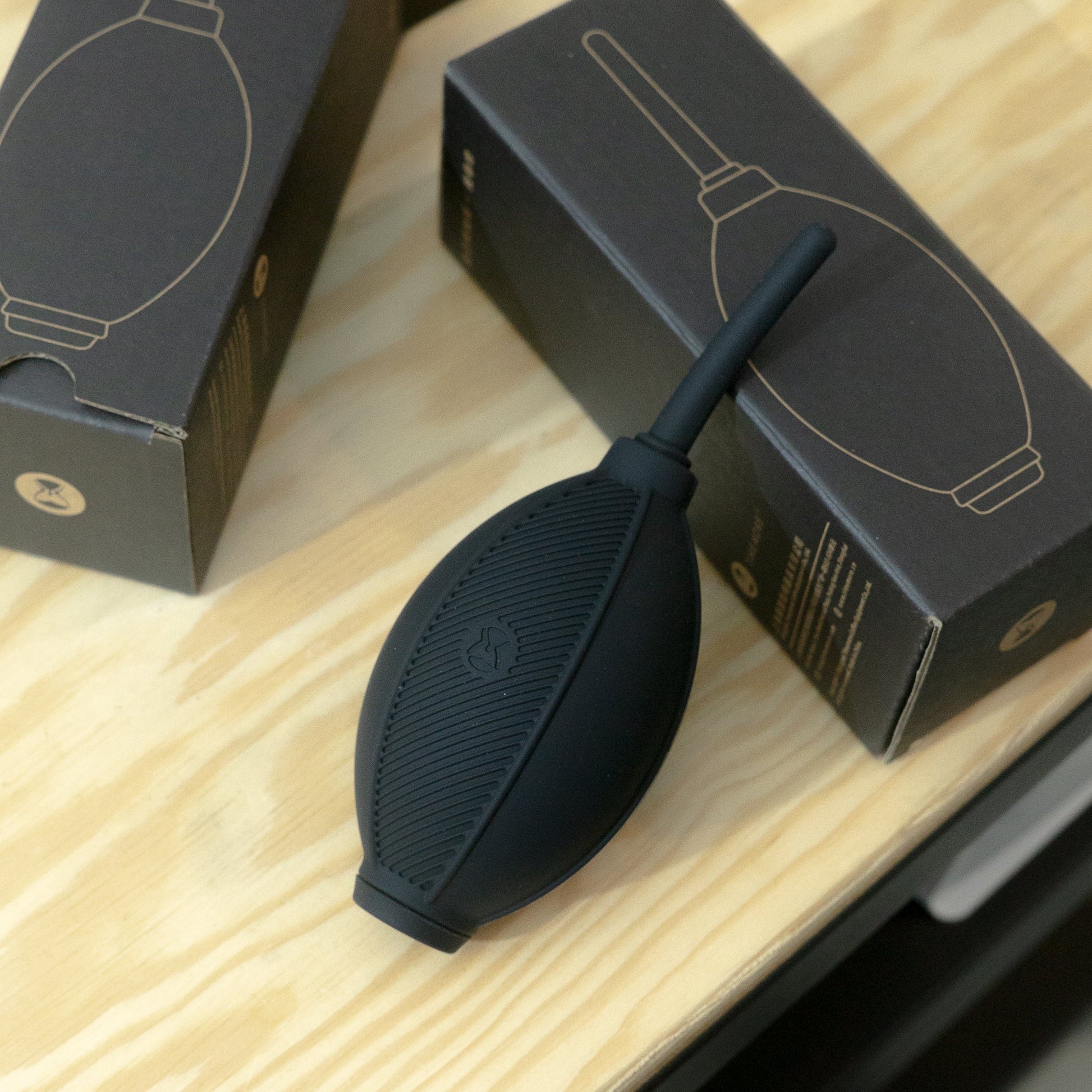 Black coffee blower tool with packaging on a wooden surface