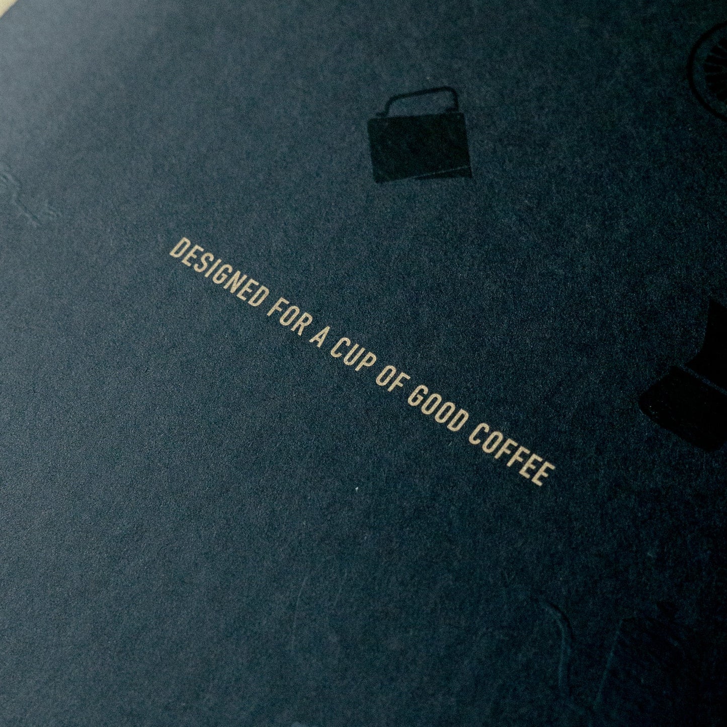 Black coffee server packaging with text and a brand logo on a wooden surface